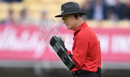 Cricket Umpire Bruce Oxford wearing a shield like device on his arm known as the arm guard to protect his head